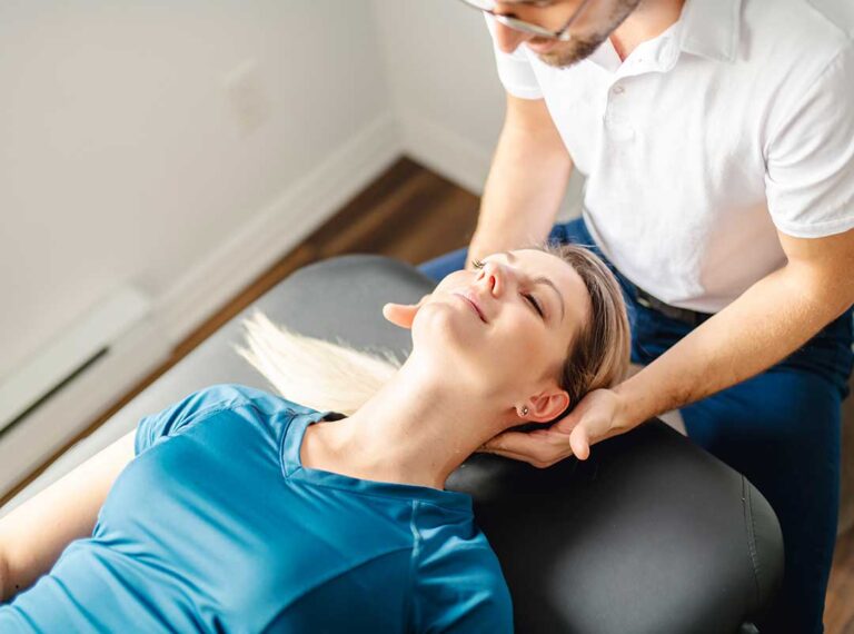 A person gently massaging their jaw while sitting with good posture at a desk.