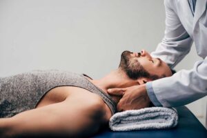 Person seated calmly while a clinician discusses neck tension in a bright treatment room.